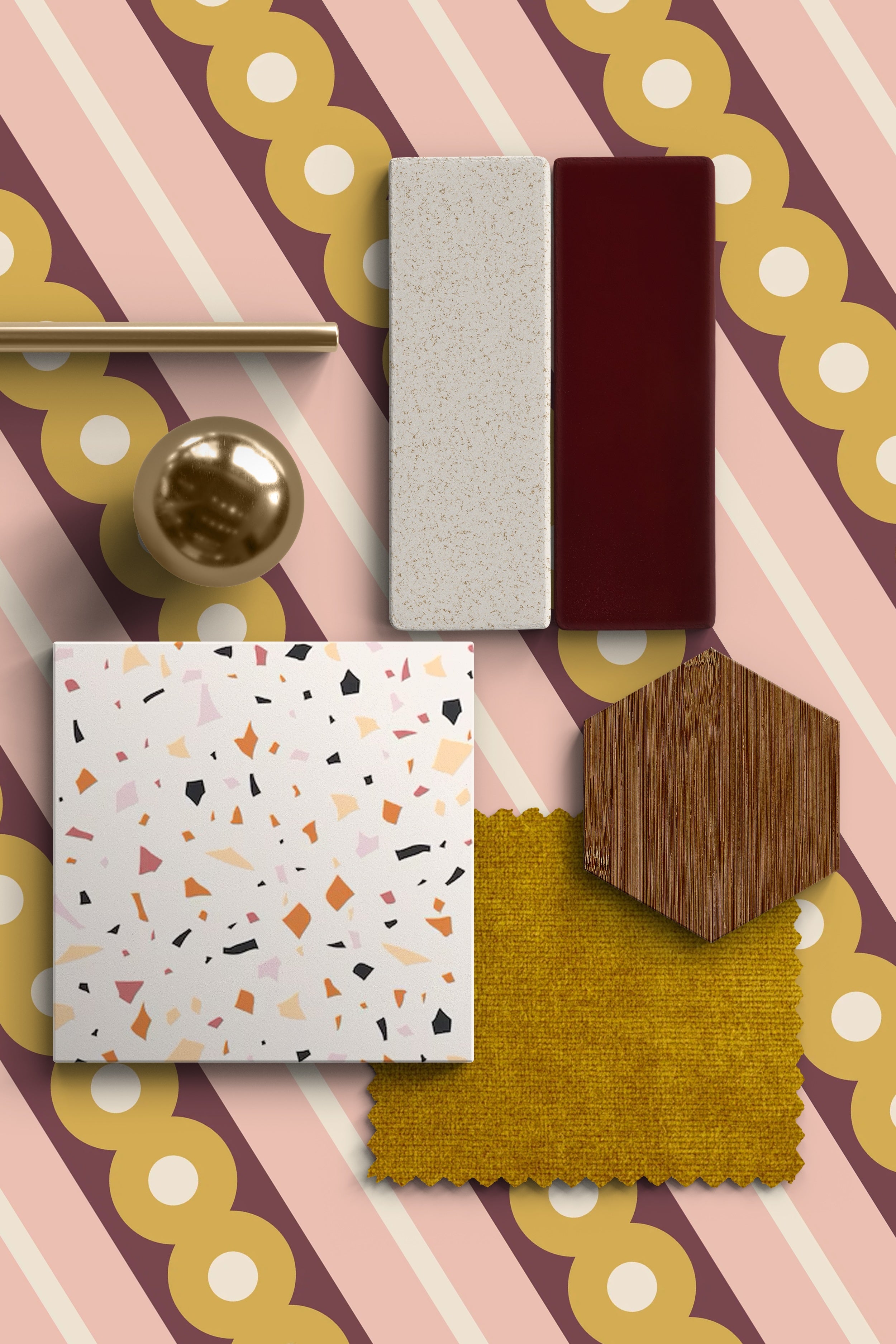 A moodboard arranged on a pink, maroon, and mustard striped wallpaper with scalloped circle details, featuring a terrazzo tile, a mustard fabric swatch, a hexagon wood sample, a brass sphere, a brass rod, and two rectangular surface samples in cream speckle and deep burgundy