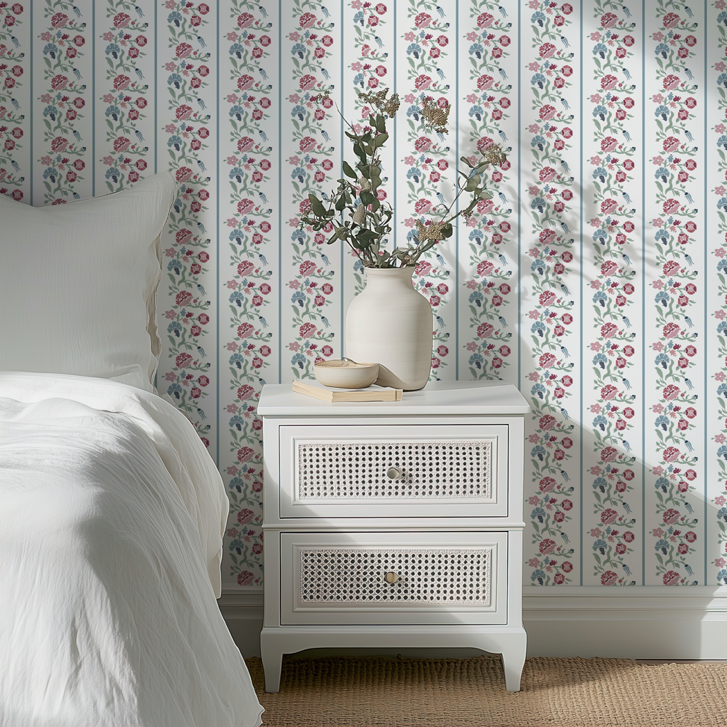 Garden Stripe floral wallpaper with vertical botanical stripes styled in a bedroom behind a white nightstand with vase and bedding