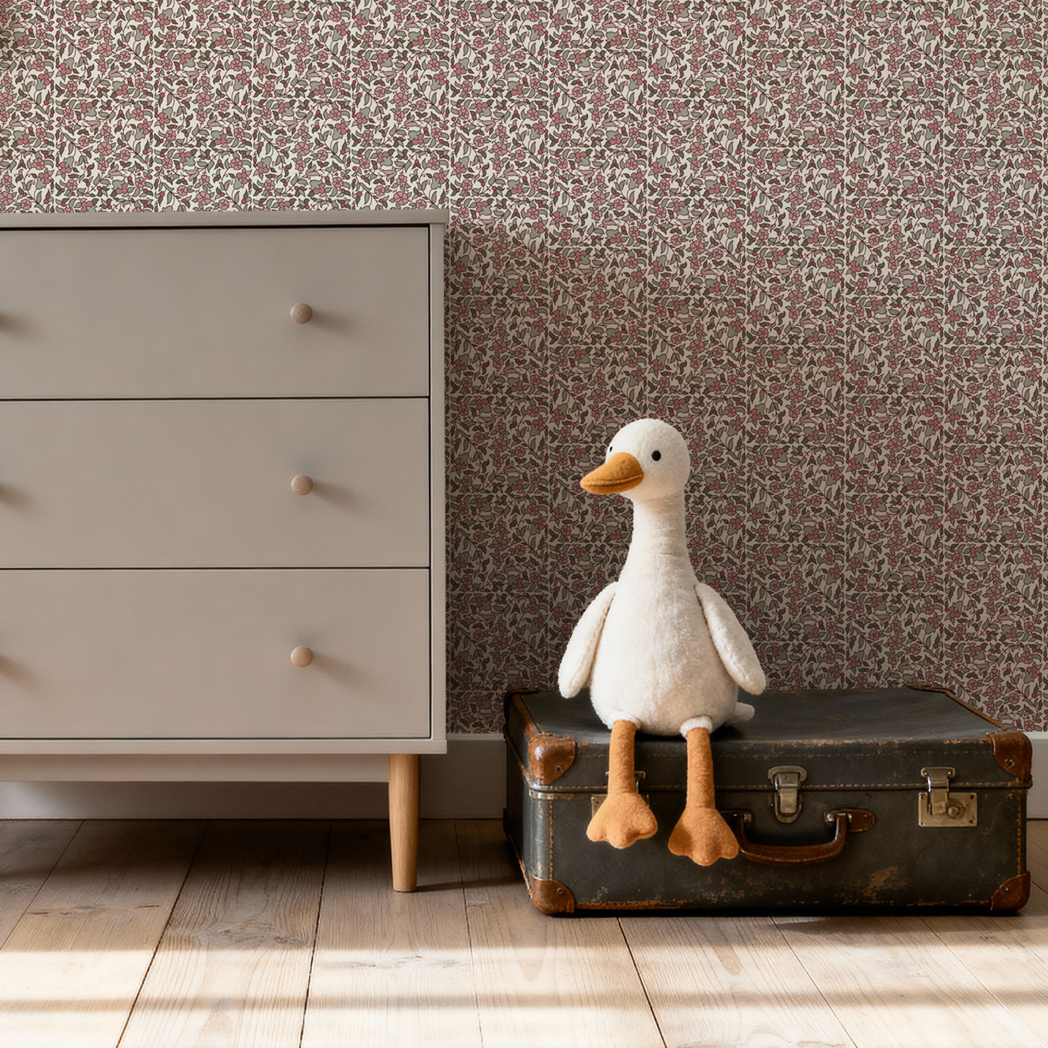 Stuffed goose on an old suitcase next to a dresser with patterned wallpaper.