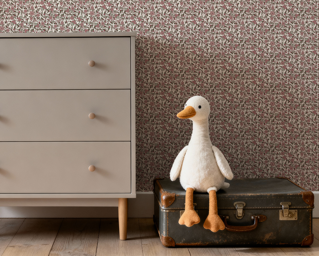 Stuffed goose on an old suitcase next to a dresser with patterned wallpaper.