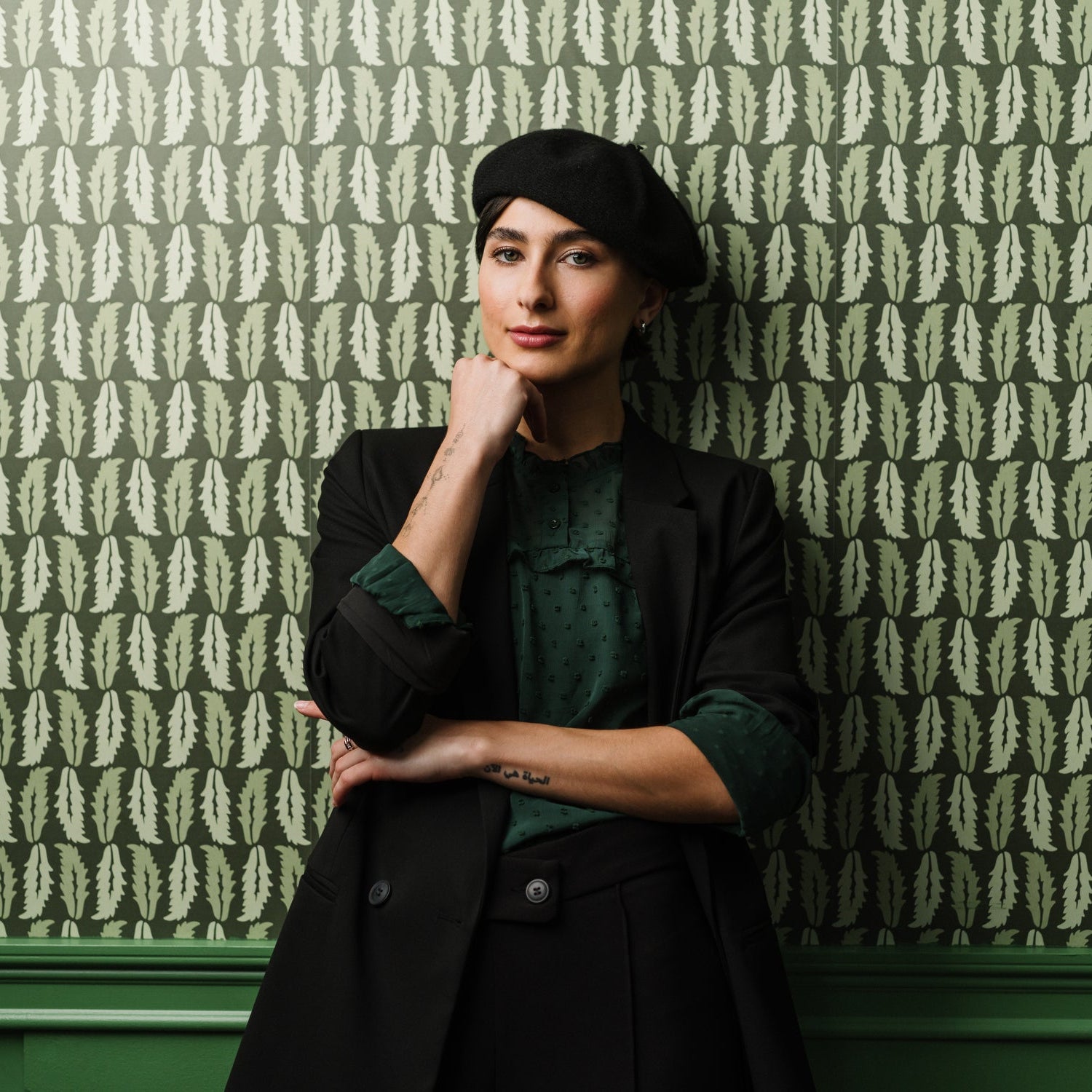 Woman standing against Sweet Chestnut wallpaper in dark green styled in a moody interior