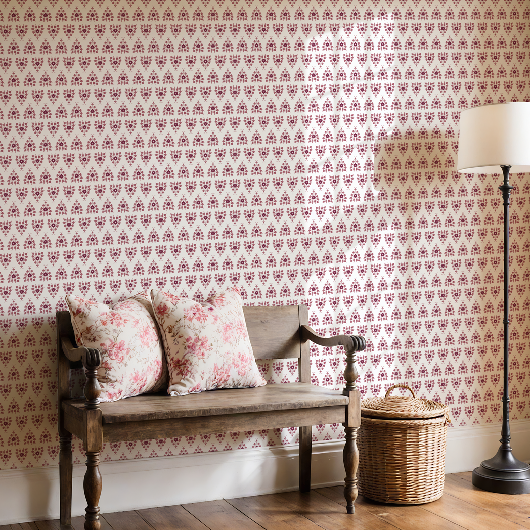 Wooden bench with floral cushions against a patterned wallpaper wall.