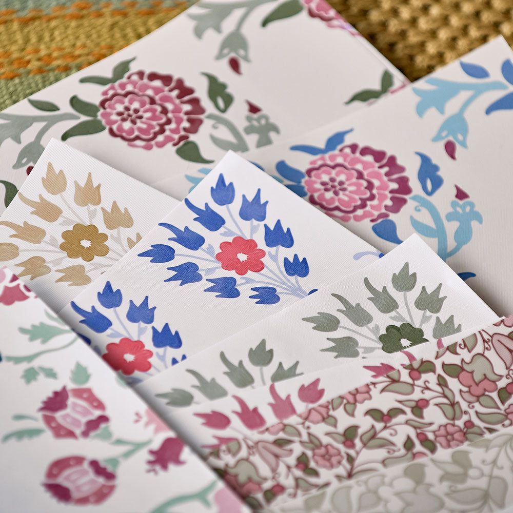 Assorted floral wallpaper samples layered together, featuring muted blues, pinks, greens, and classic heritage motifs.