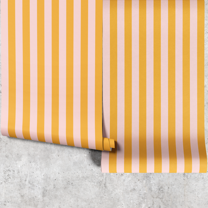 Two panels of yellow and pink thin stripe wallpaper hanging against a concrete wall
