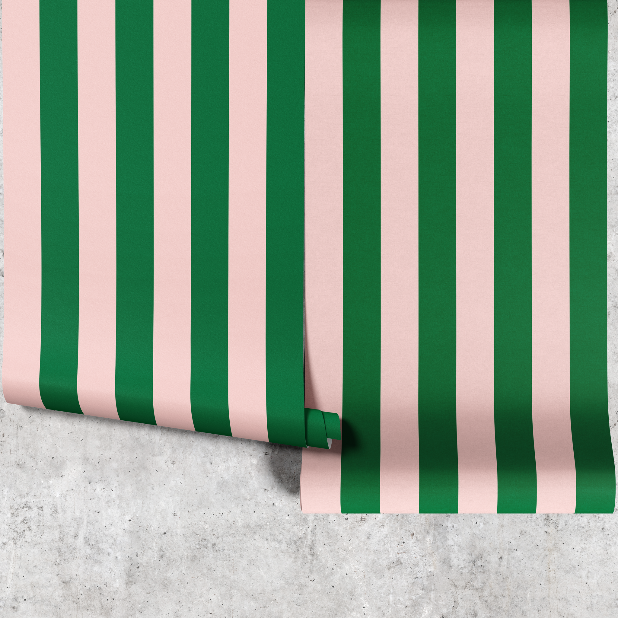 Two panels of pink and green wide stripe wallpaper hanging against a concrete wall
