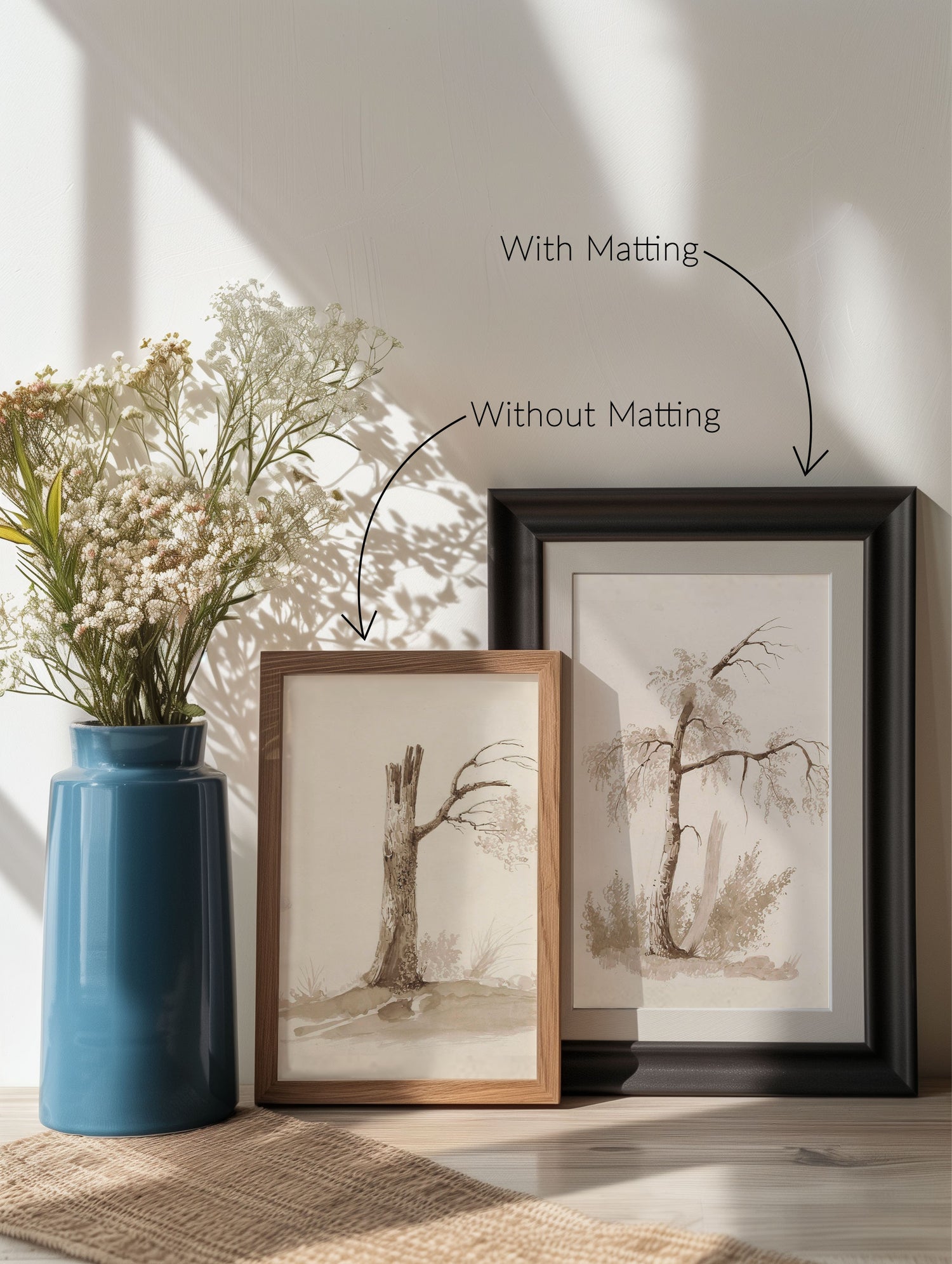 A set of two frames leaning against a wall with a blue vase and flowers next to them