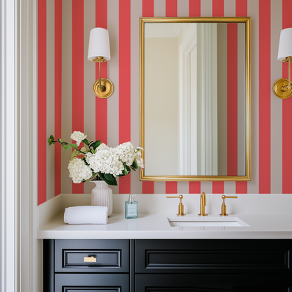 A black vanity in a powder room with gold accents and orange and beige wallpaper behind it