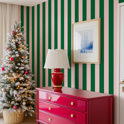 The corner of a living room dressed for the Holidays with a hot pink dresser and pink and green wide stripe wallpaper