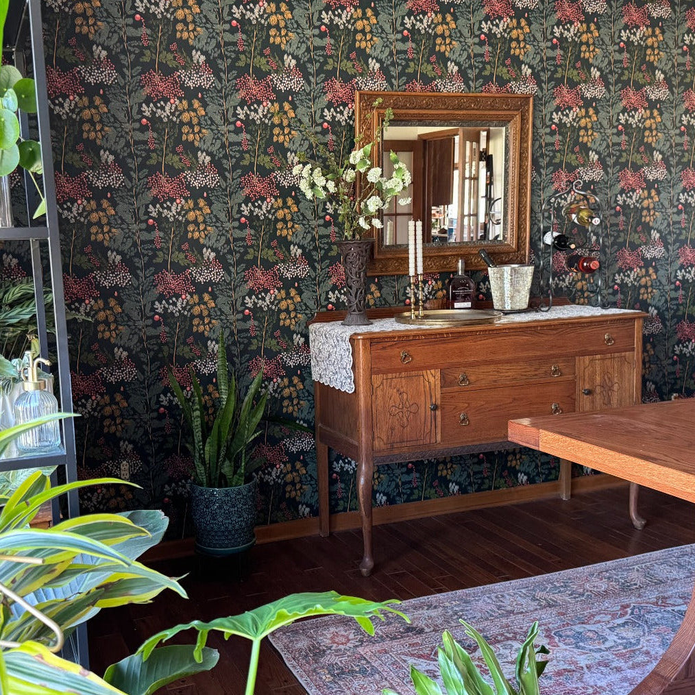Dining room with wooden furniture, floral wallpaper, and potted plants.