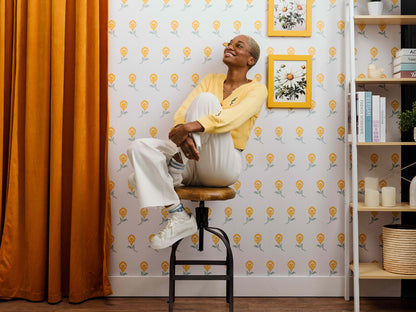 Dancing Iris wallpaper in yellow styled in a floral interior with a happy woman and curtains - Huggleberry Hill
