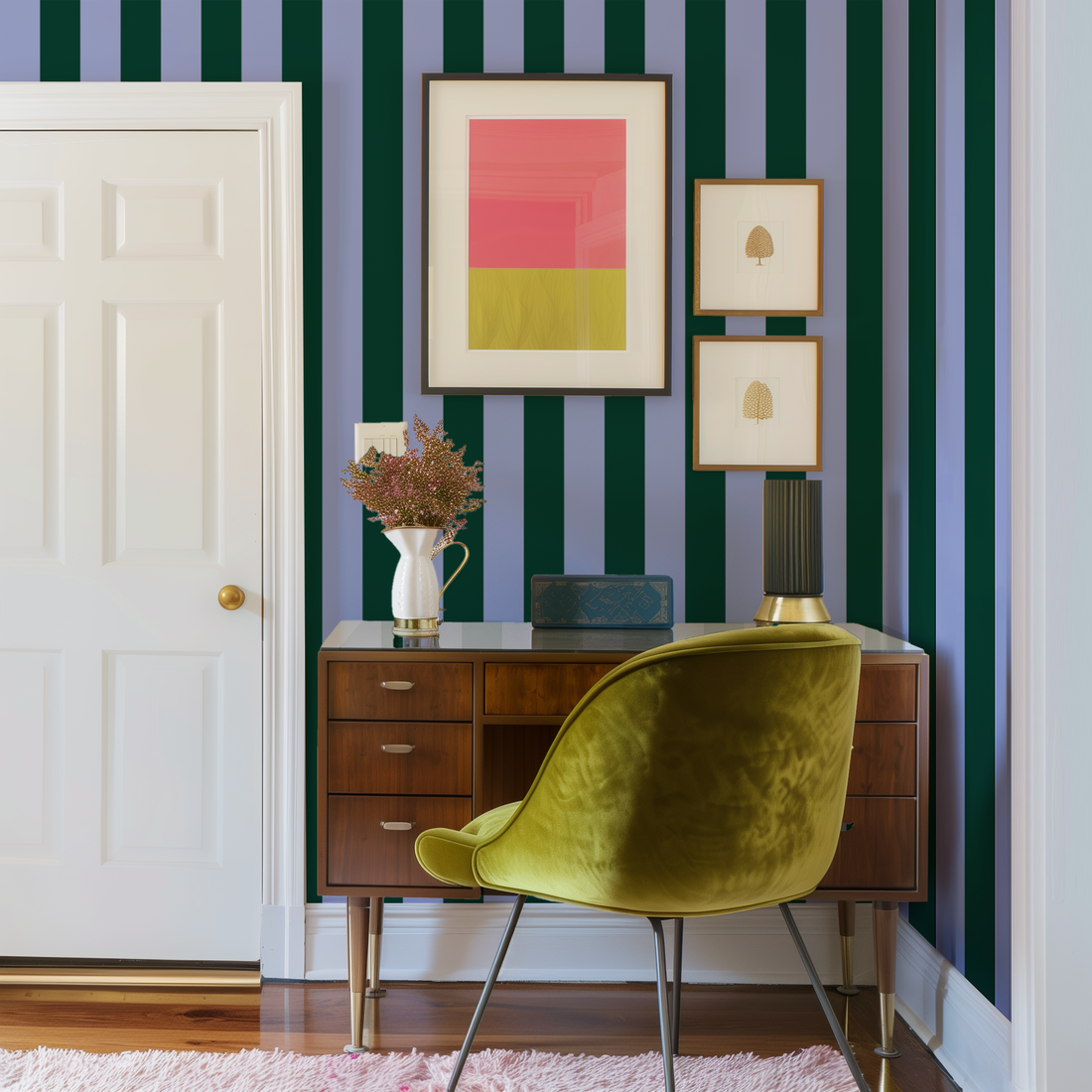 A midcentury desk and velvet green chair in the corner of a room with blue and green wallpaper behind it 