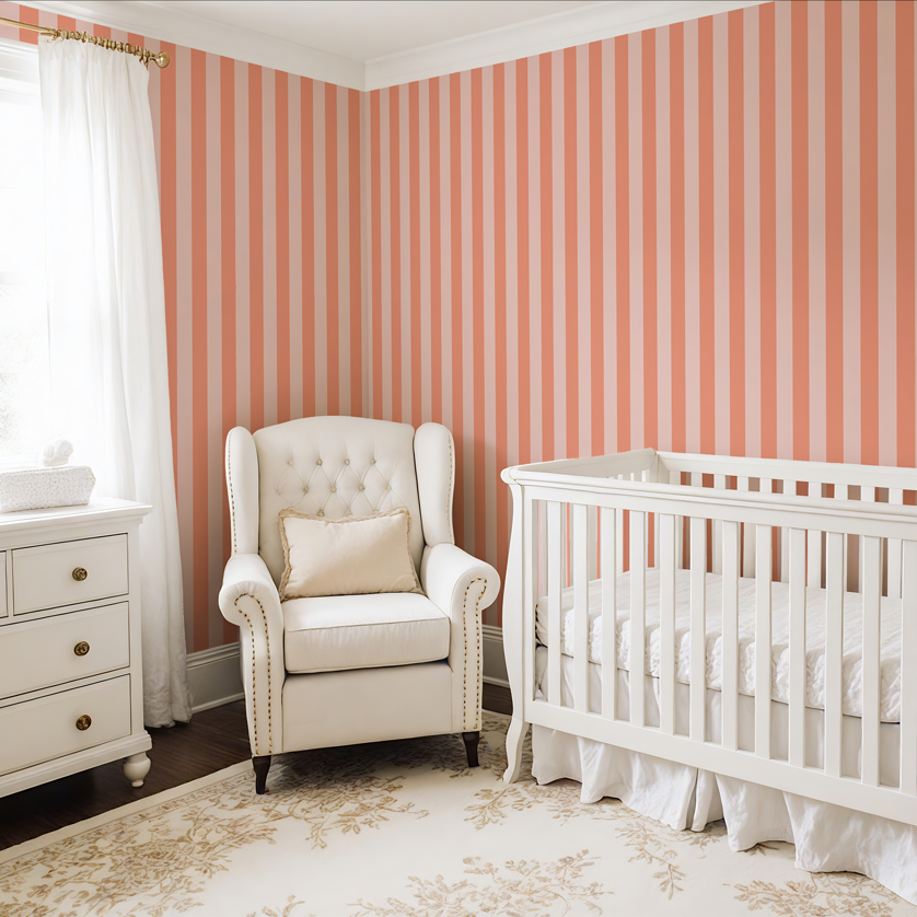 Peach and pink thin stripe wallpaper in a soft nursery with white crib, armchair, and natural light