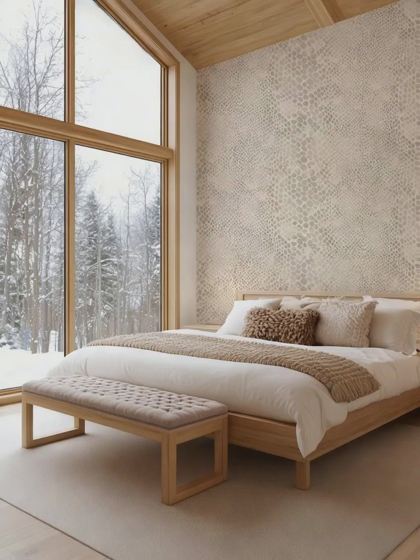 A cabin resort bedroom with neutral snakeskin pattern wallpaper and snow falling outside