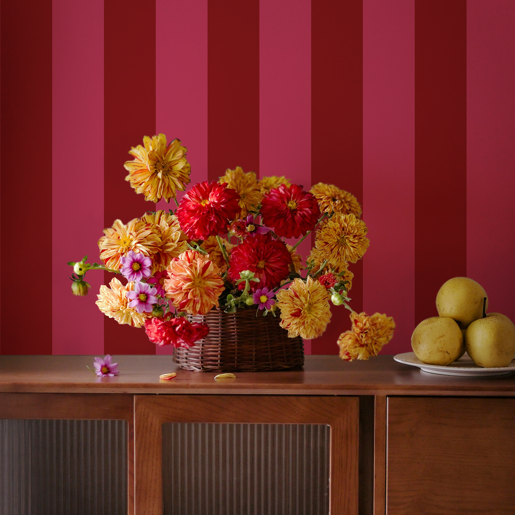 Red and pink wide stripe wallpaper with warm floral arrangement on a wooden console table