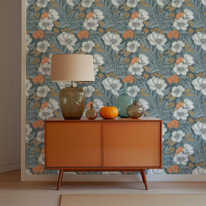 A midcentury dresser with a glass lamp and glass vases in front of a wall with blue poppy wallpaper.