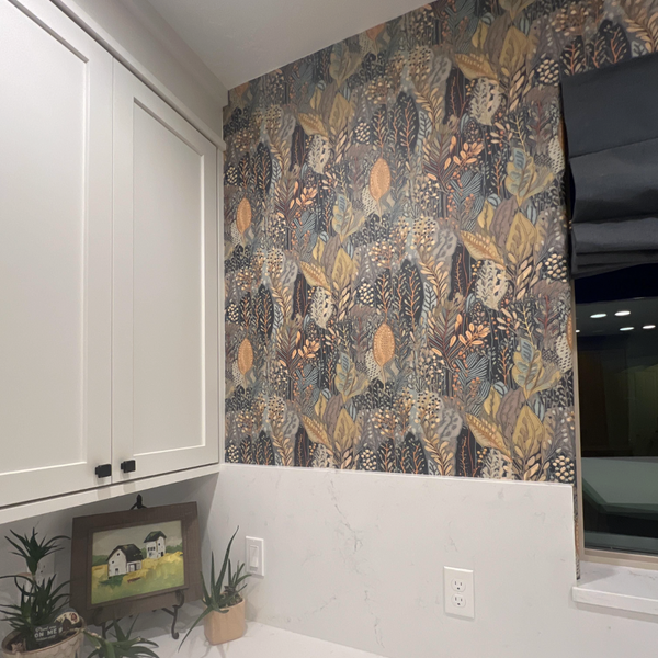 Room interior with patterned wallpaper, white cabinets, and plants.