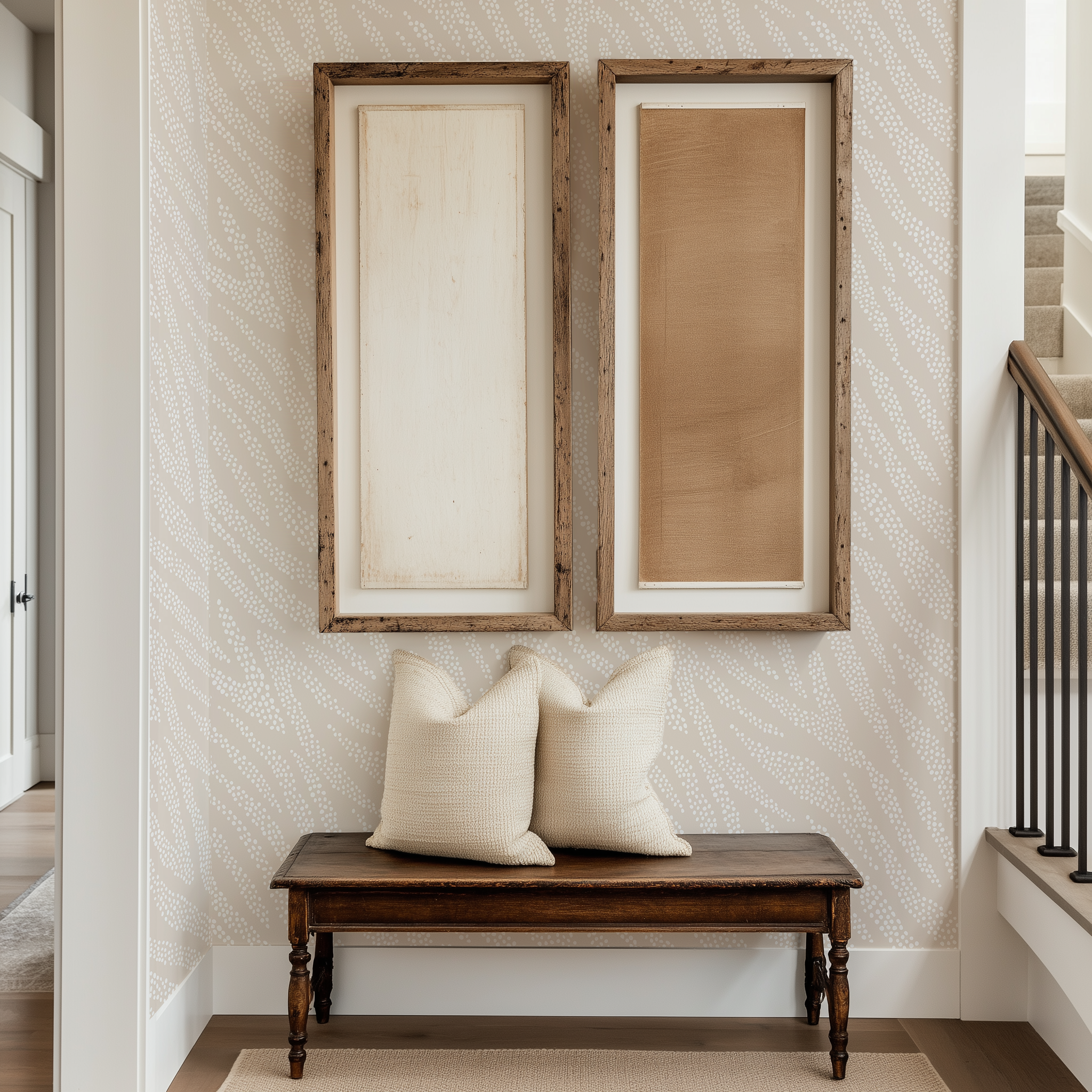 A light and airy hallway with an antique bench and modern rustic wall art. There is a modern cream and white dotty animal print wallpaper behind the bench.