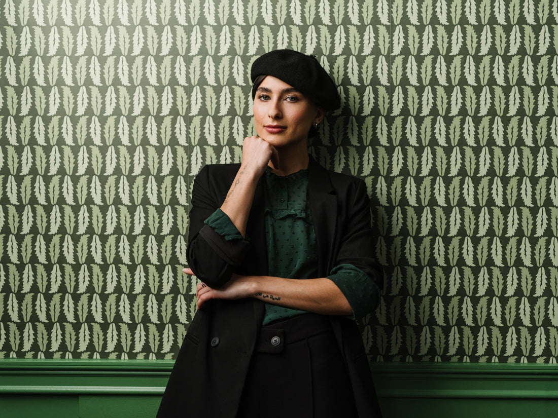 Woman standing against Sweet Chestnut wallpaper in dark green styled in a moody interior