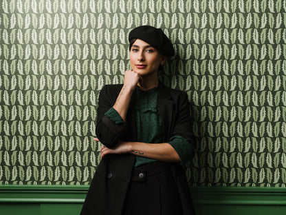 Woman standing against Sweet Chestnut wallpaper in dark green styled in a moody interior
