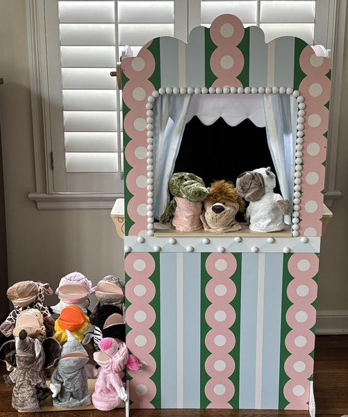 Puppet theater with colorful striped design and various puppets on a wooden floor.