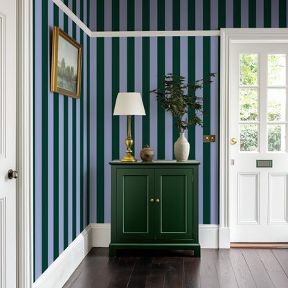 The entryway in a Victorian house with blue and green wallpaper and a dark green sideboard